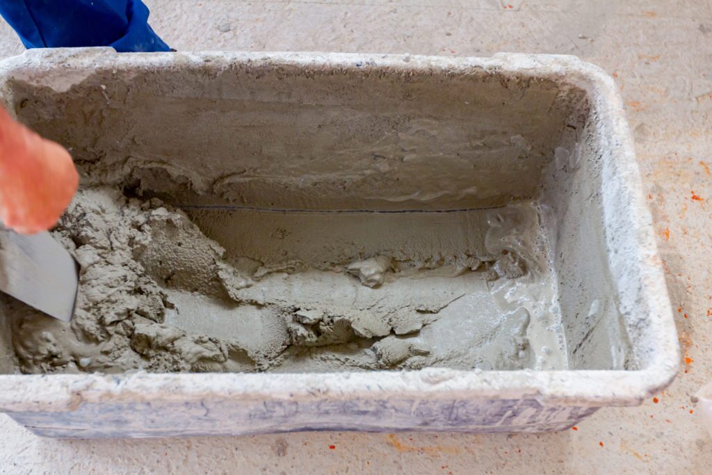 Builder is using spatula, trowel to take mortar